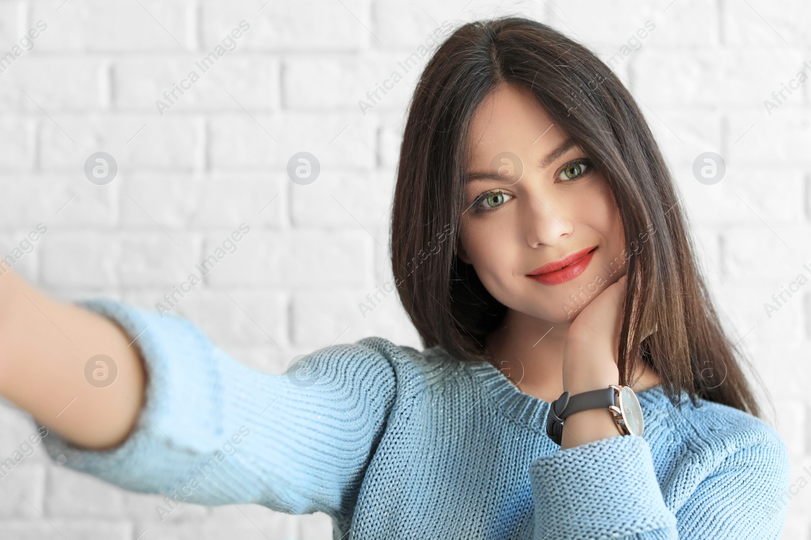 Photo of Attractive young woman taking selfie near brick wall