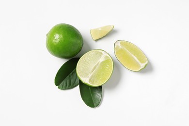 Photo of Fresh ripe limes and leaves on white background, flat lay
