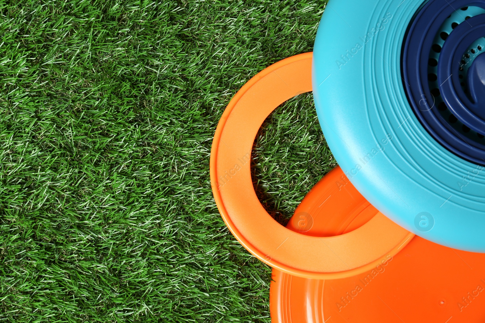 Photo of Plastic frisbee disks and ring on green grass, flat lay. Space for text