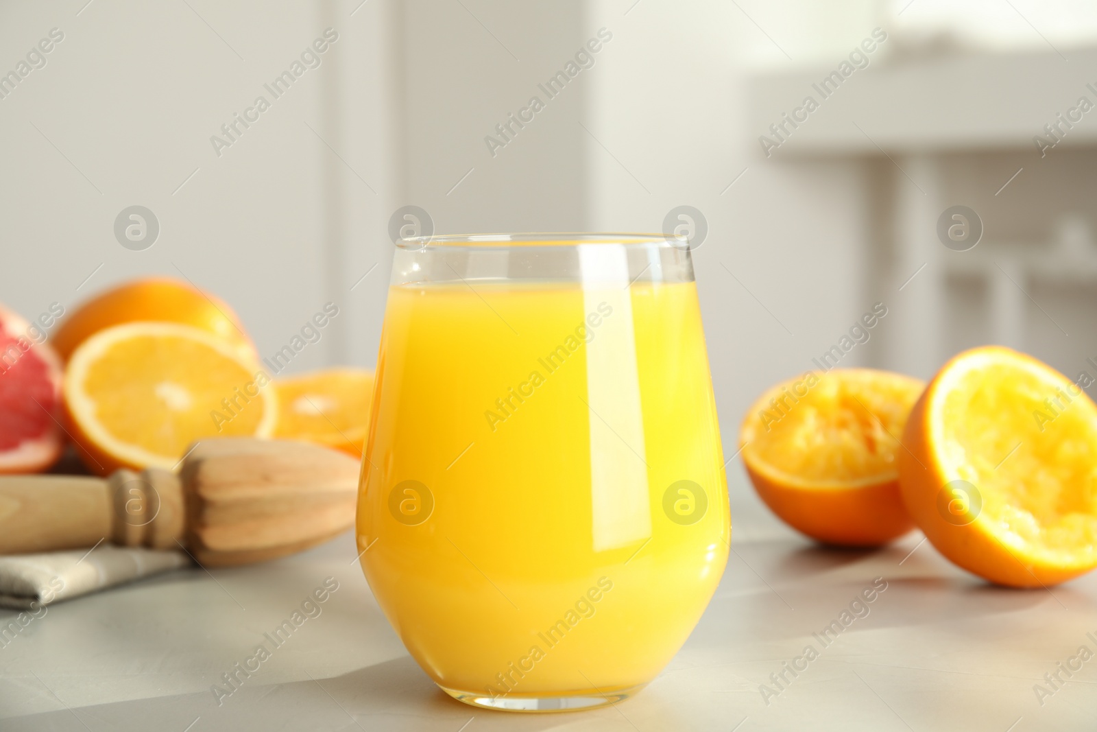 Photo of Freshly made juice, oranges and reamer on table, closeup