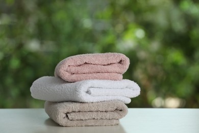 Photo of Stacked towels on white table against blurred background