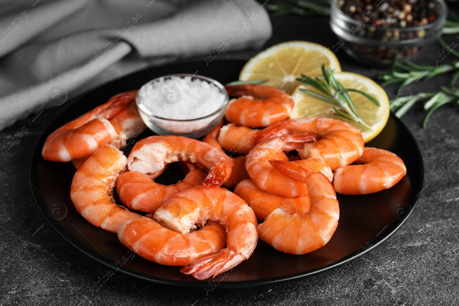 Photo of Delicious cooked shrimps with salt and lemon on dark grey table