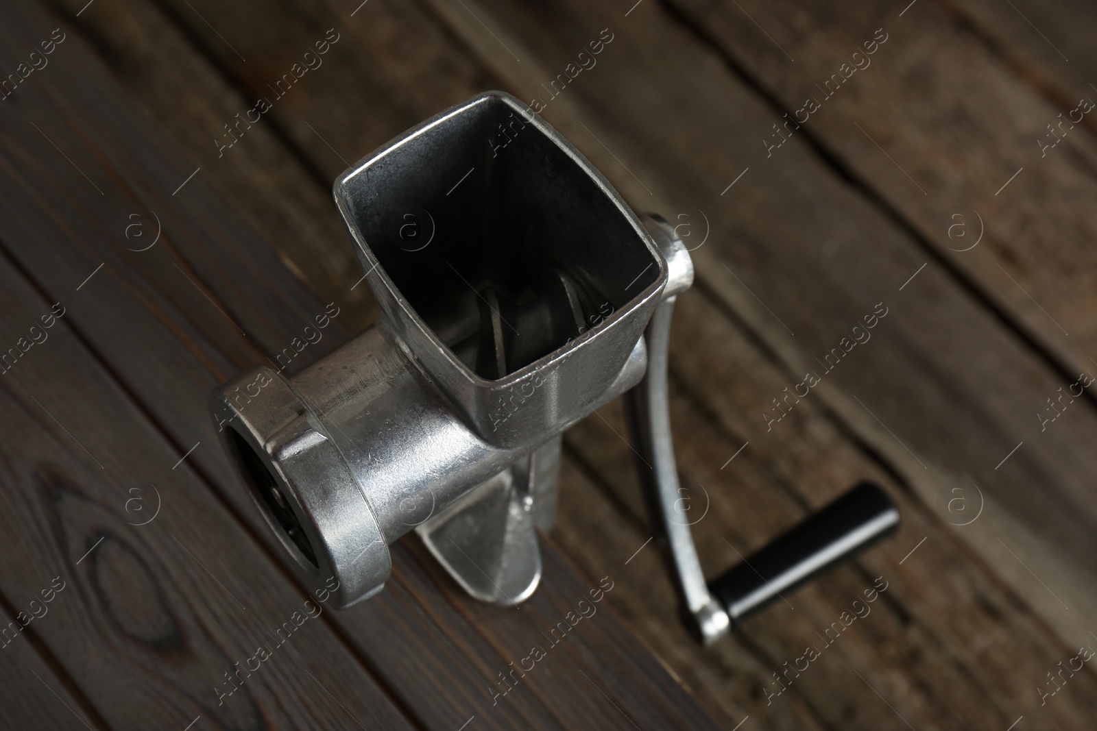 Photo of Metal manual meat grinder on wooden table, above view