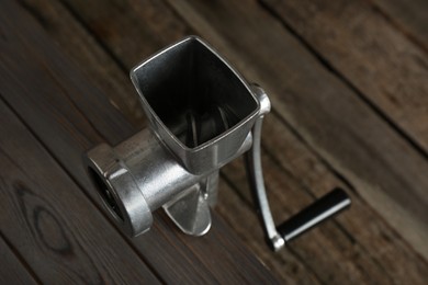 Photo of Metal manual meat grinder on wooden table, above view