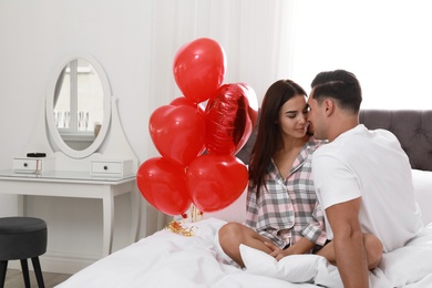 Photo of Beautiful couple with heart shaped balloons in bedroom