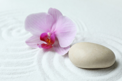 Photo of Stone and beautiful flower on sand with pattern. Zen, meditation, harmony