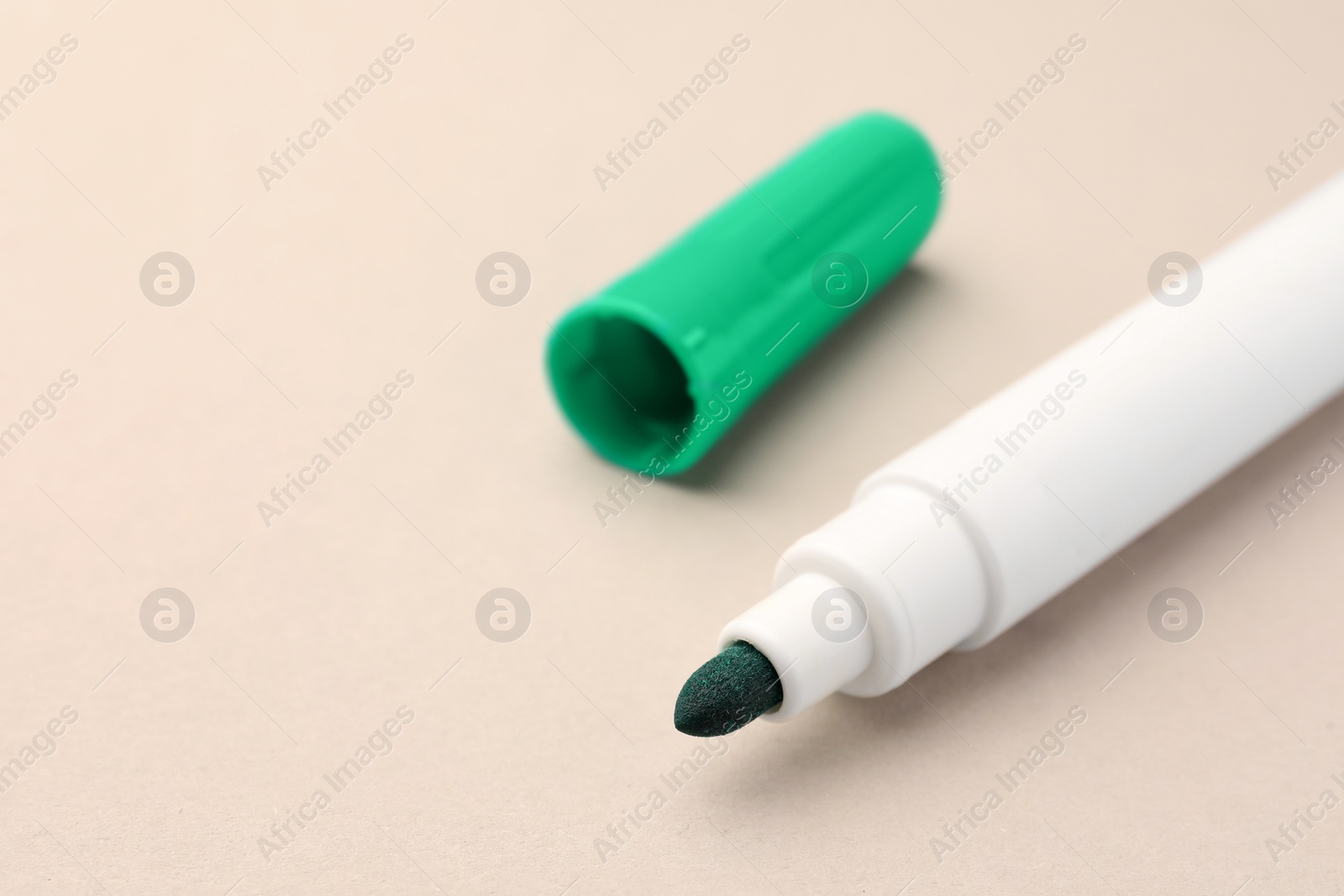 Photo of Bright green marker on beige background, closeup. Space for text