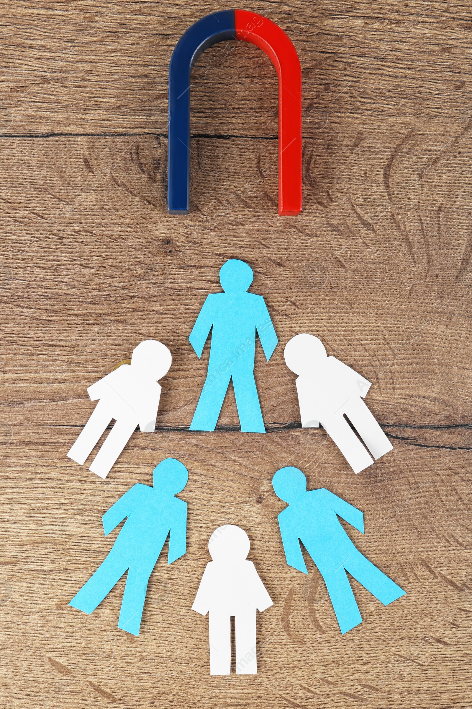 Photo of Magnet and paper people on wooden table, flat lay