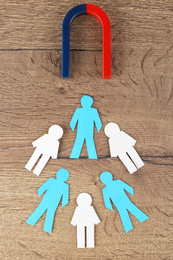 Magnet and paper people on wooden table, flat lay