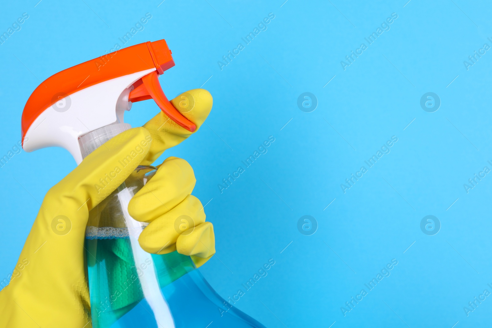 Photo of Woman holding plastic spray bottle on light blue background, closeup. Space for text