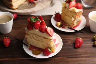 Photo of Tasty cake with fresh strawberries, mint and cups of drink on wooden table