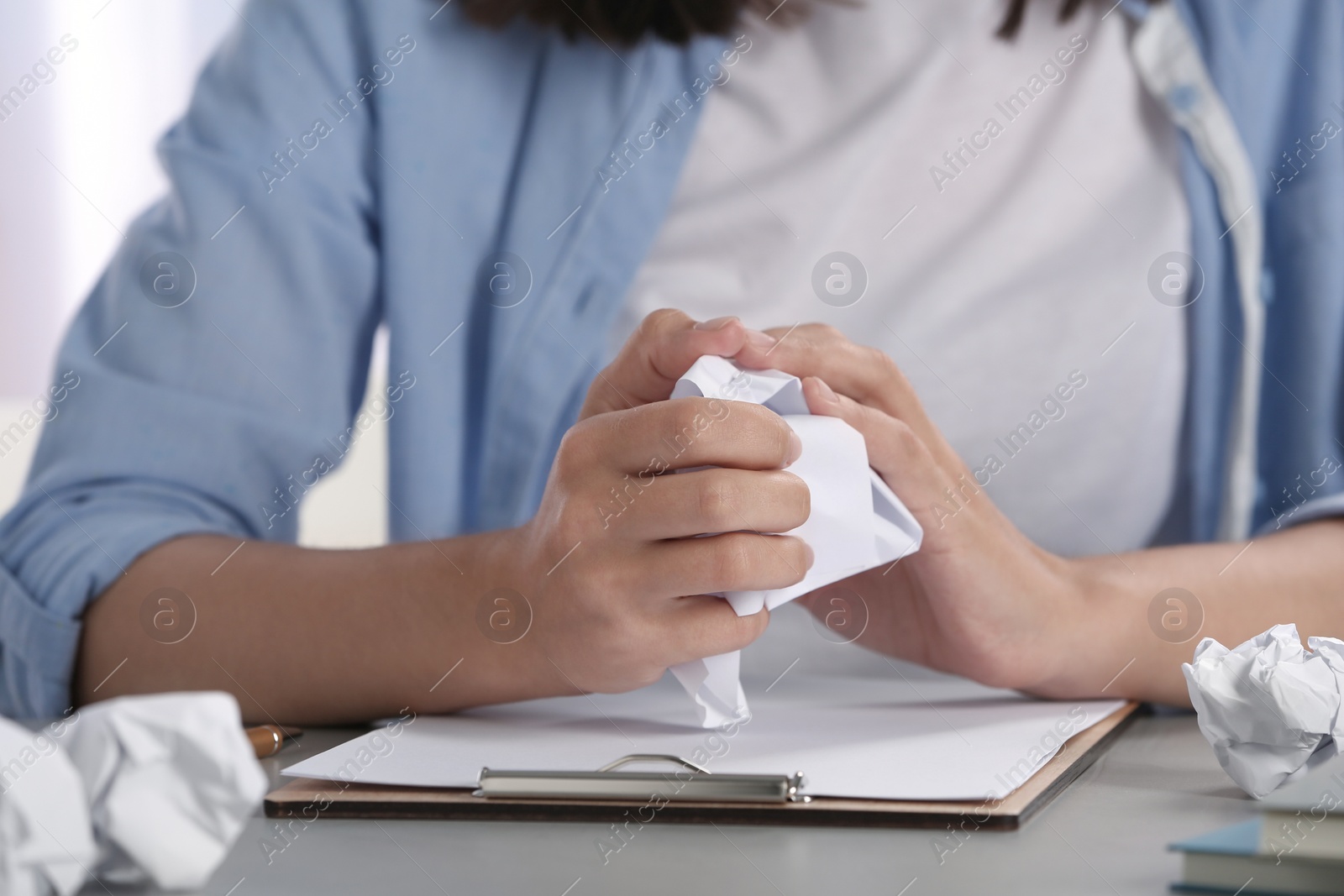 Photo of Woman crumpling paper at table, closeup. Generating idea