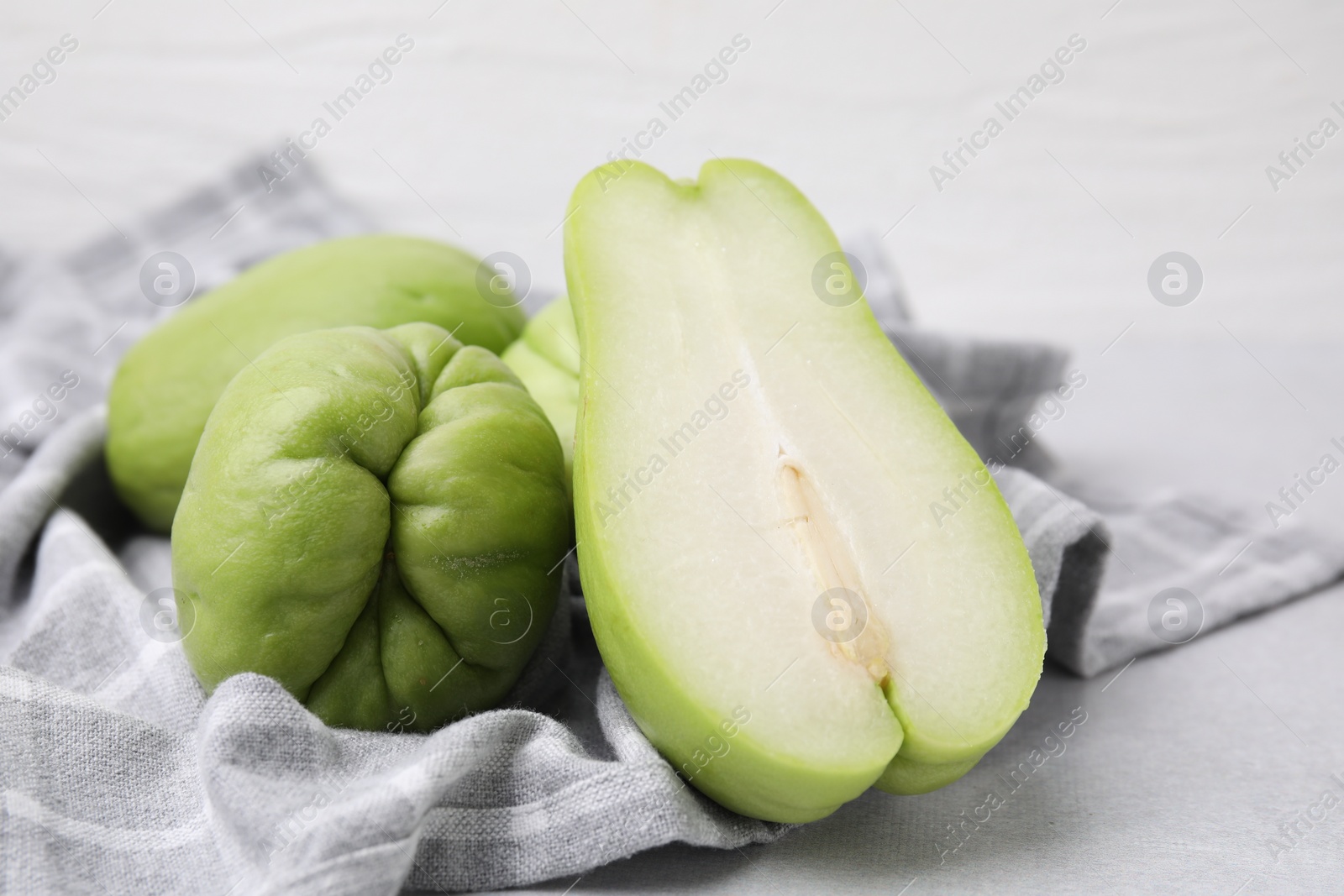 Photo of Cut and whole chayote on gray table, closeup