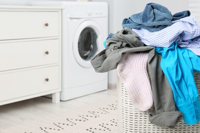 Plastic laundry basket overfilled with clothes in bathroom, closeup. Space for text