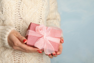 Photo of Young woman holding Christmas gift on blue background, closeup