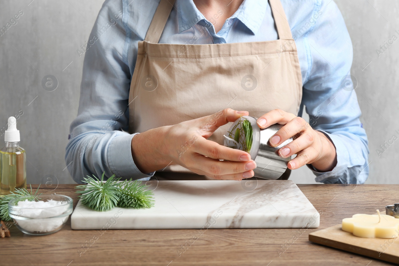 Photo of Woman making conifer candle at table, closeup