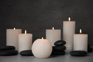 Photo of Burning candles and spa stones on grey table