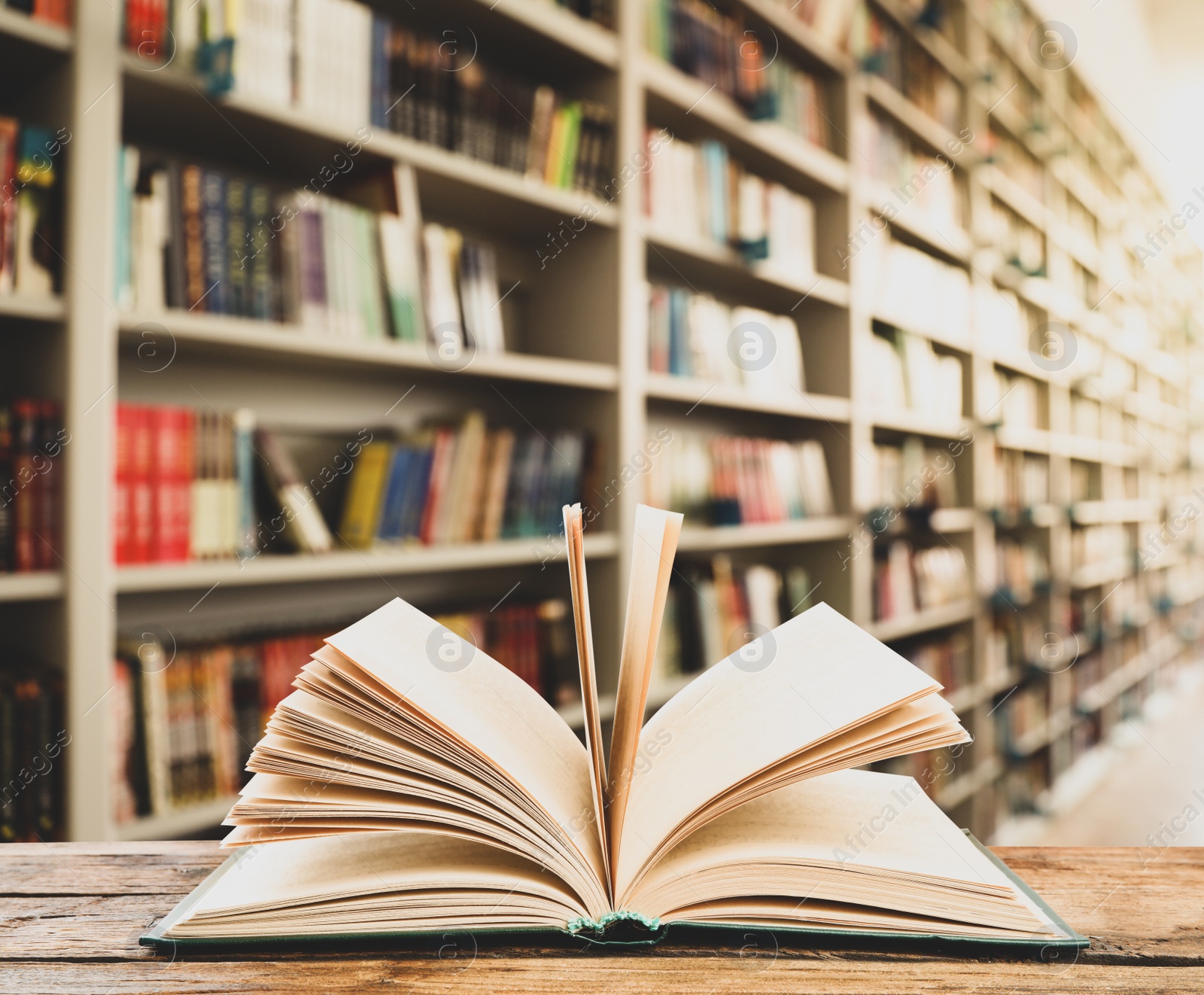 Image of Open hardcover book on wooden table in library