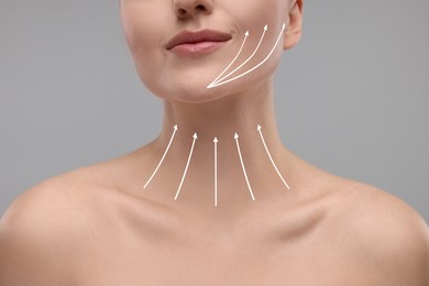 Image of Woman with perfect skin after cosmetic treatment on grey background, closeup. Lifting arrows on her neck and face