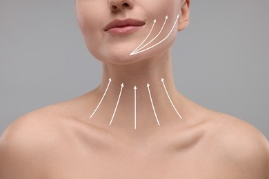 Woman with perfect skin after cosmetic treatment on grey background, closeup. Lifting arrows on her neck and face