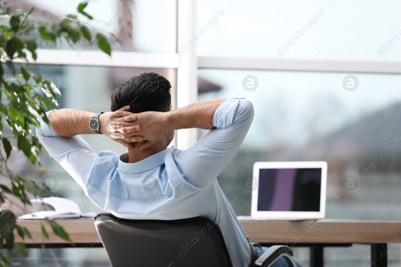 Photo of Businessman relaxing in office chair at workplace, back view. Space for text