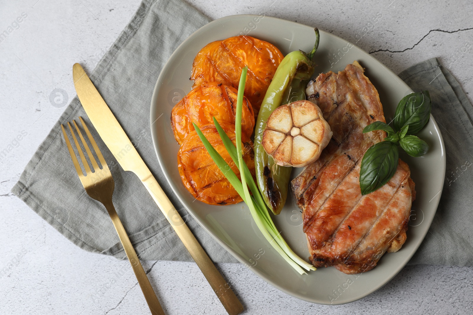 Photo of Delicious grilled meat and vegetables served on light grey table, flat lay