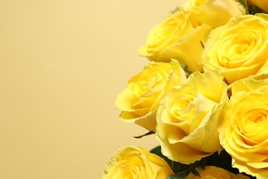 Photo of Beautiful bouquet of yellow roses on beige background, closeup. Space for text