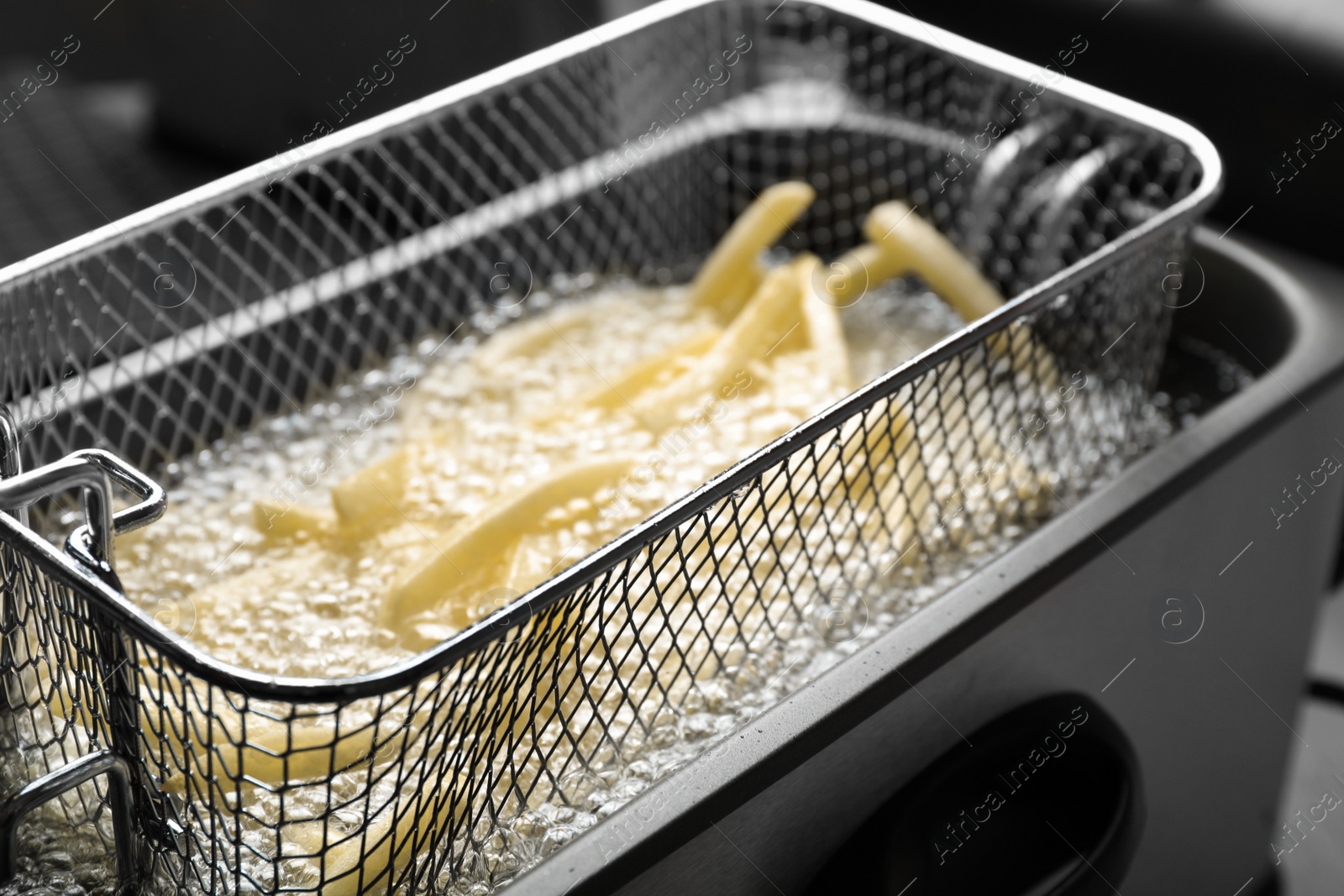 Photo of Cooking delicious french fries in hot oil, closeup