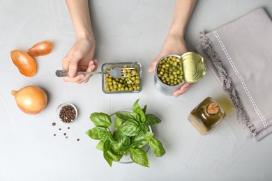 Photo of Woman with canned green peas at table, top view