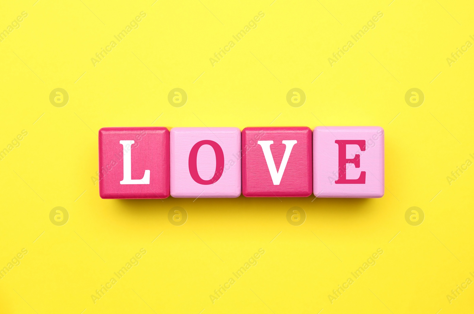 Photo of Cubes with word LOVE on yellow background, flat lay