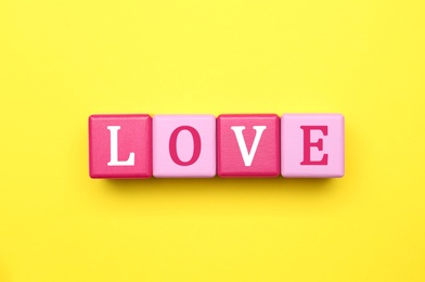 Photo of Cubes with word LOVE on yellow background, flat lay