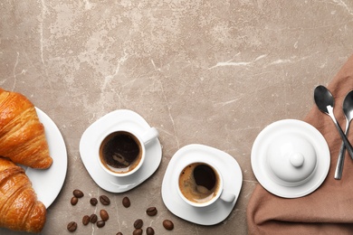 Flat lay composition with cups of coffee and croissants on grey background. Space for text