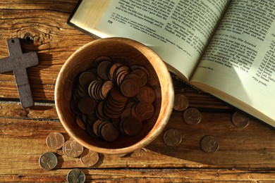 Donate and give concept. Bowl with coins, cross and Bible on wooden table, flat lay