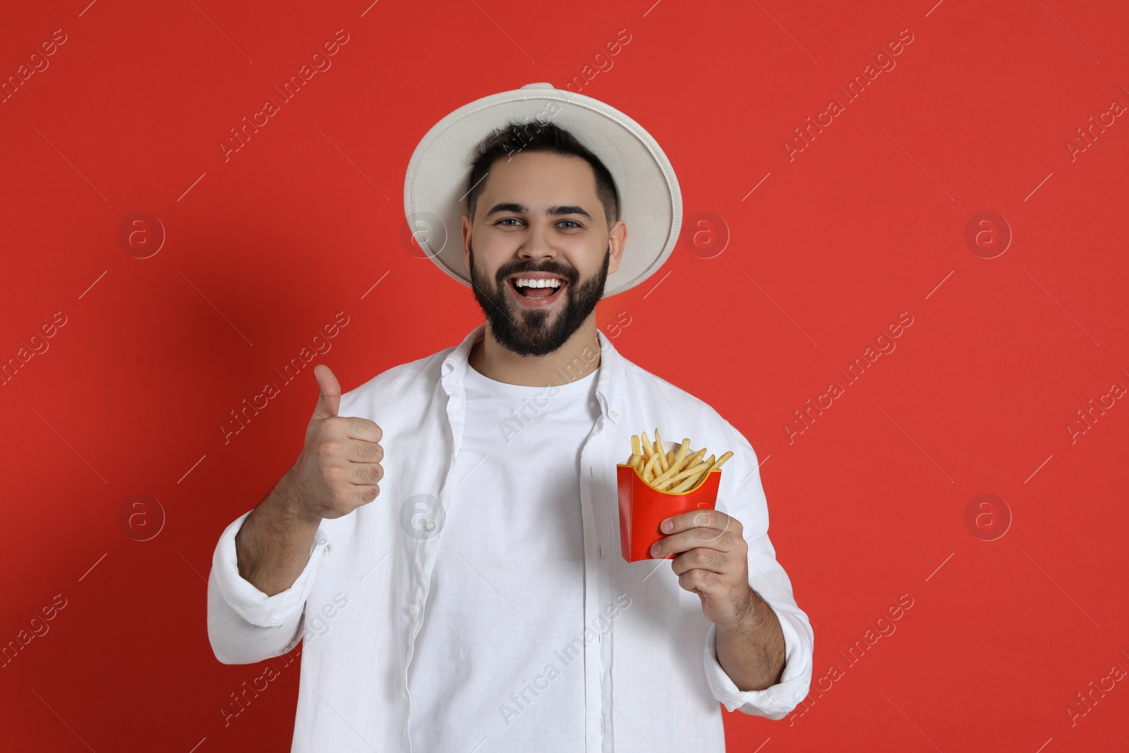 Photo of Young man with French fries on red background