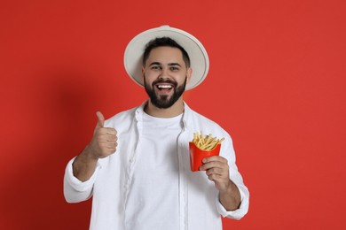 Photo of Young man with French fries on red background