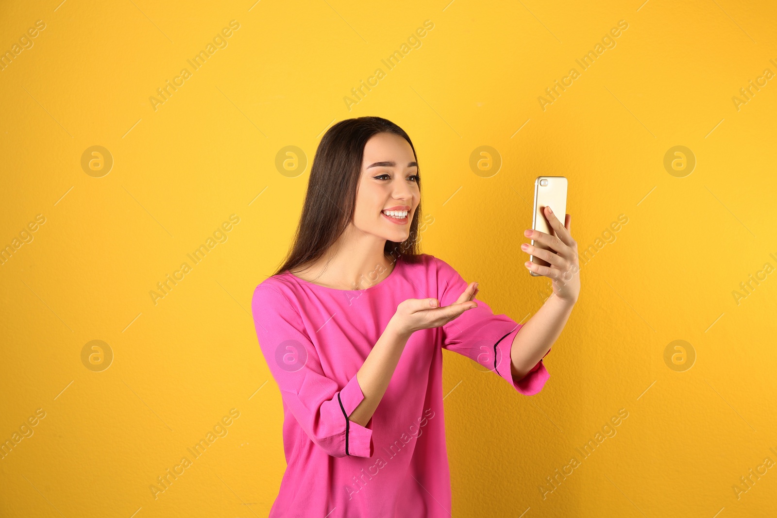 Photo of Woman using mobile phone for video chat on color background