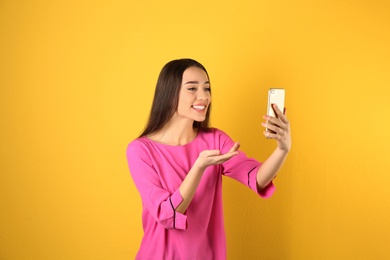 Photo of Woman using mobile phone for video chat on color background