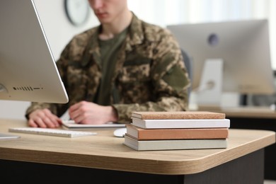 Photo of Military education. Student in soldier uniform learning at wooden table indoors, selective focus