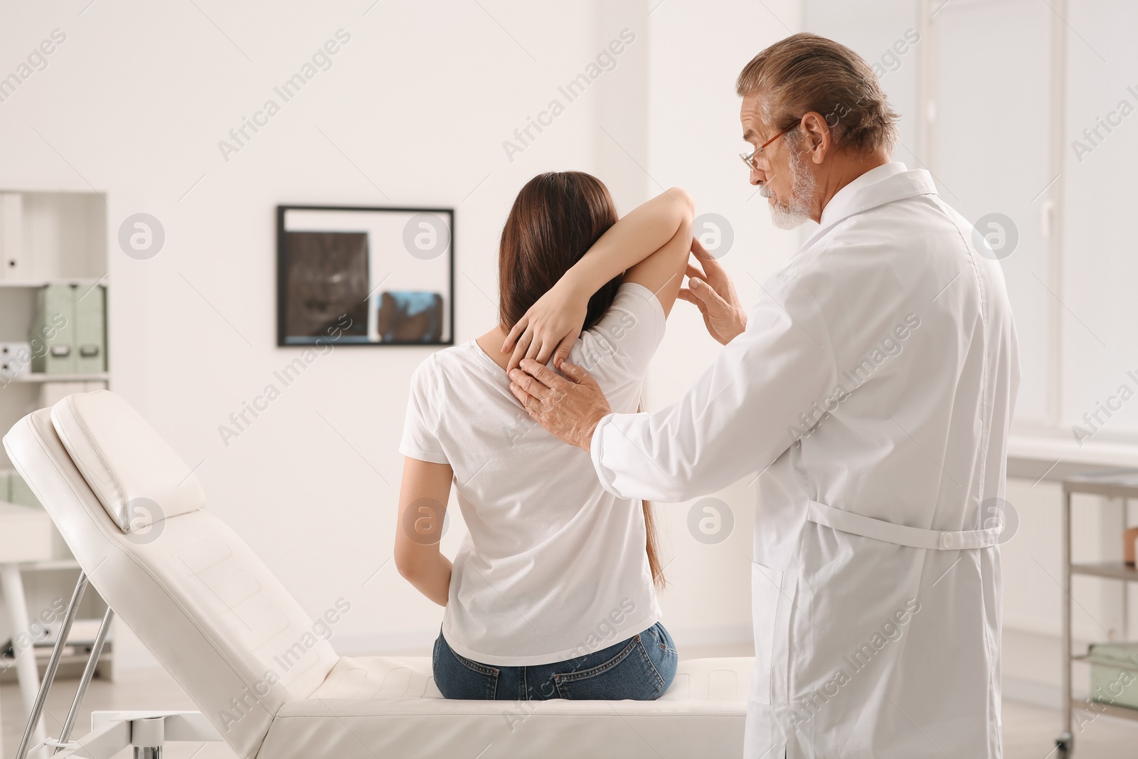 Photo of Professional orthopedist examining patient's shoulder in clinic