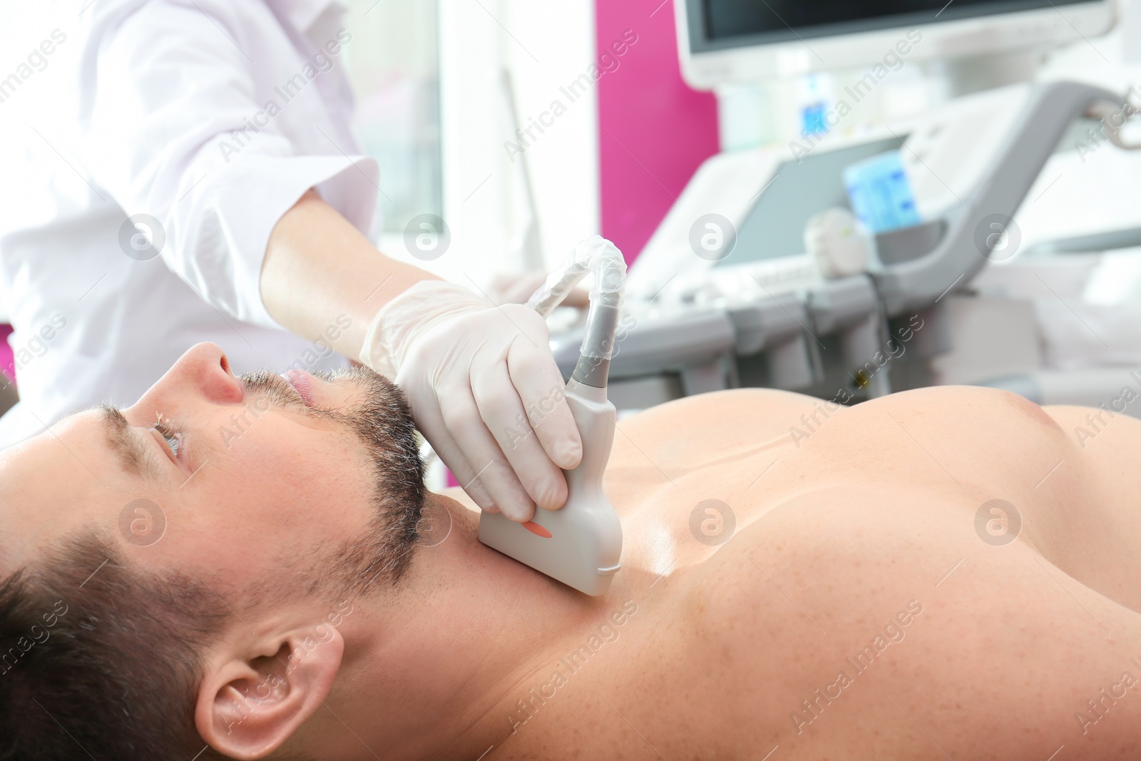 Photo of Doctor conducting ultrasound examination of thyroid gland in clinic