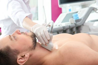 Doctor conducting ultrasound examination of thyroid gland in clinic