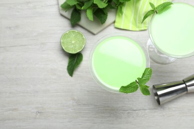 Photo of Delicious mint liqueur with green leaves on white wooden table, flat lay. Space for text