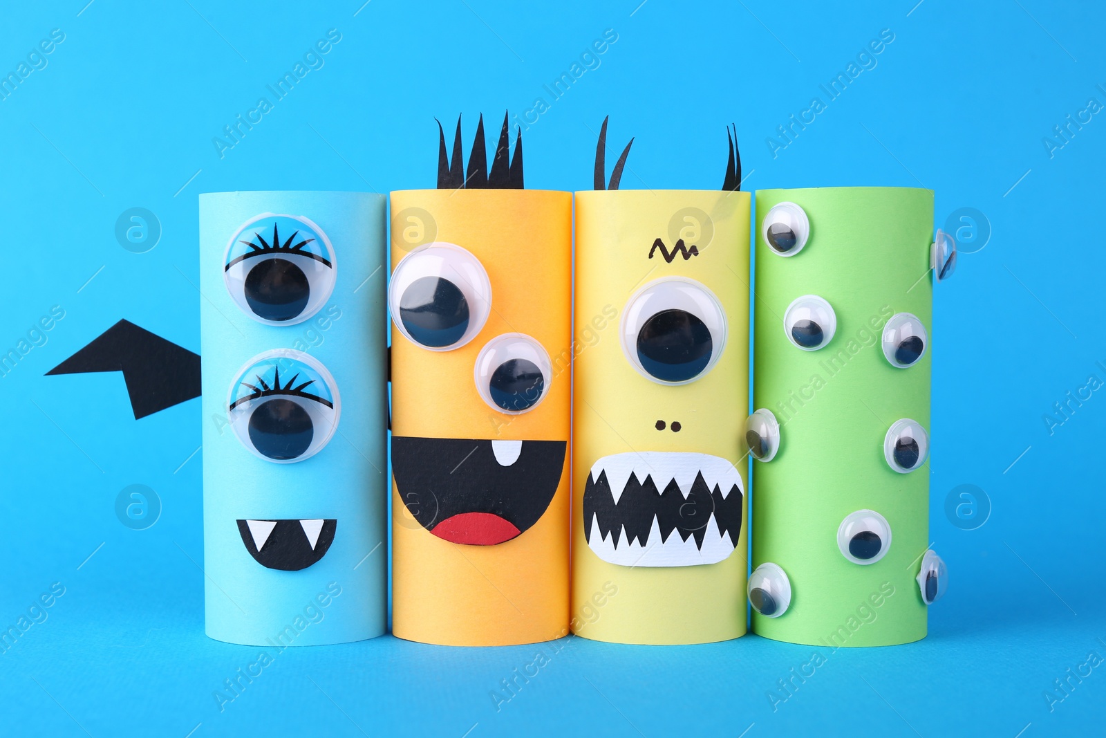 Photo of Spooky paper monsters on light blue background. Halloween decoration