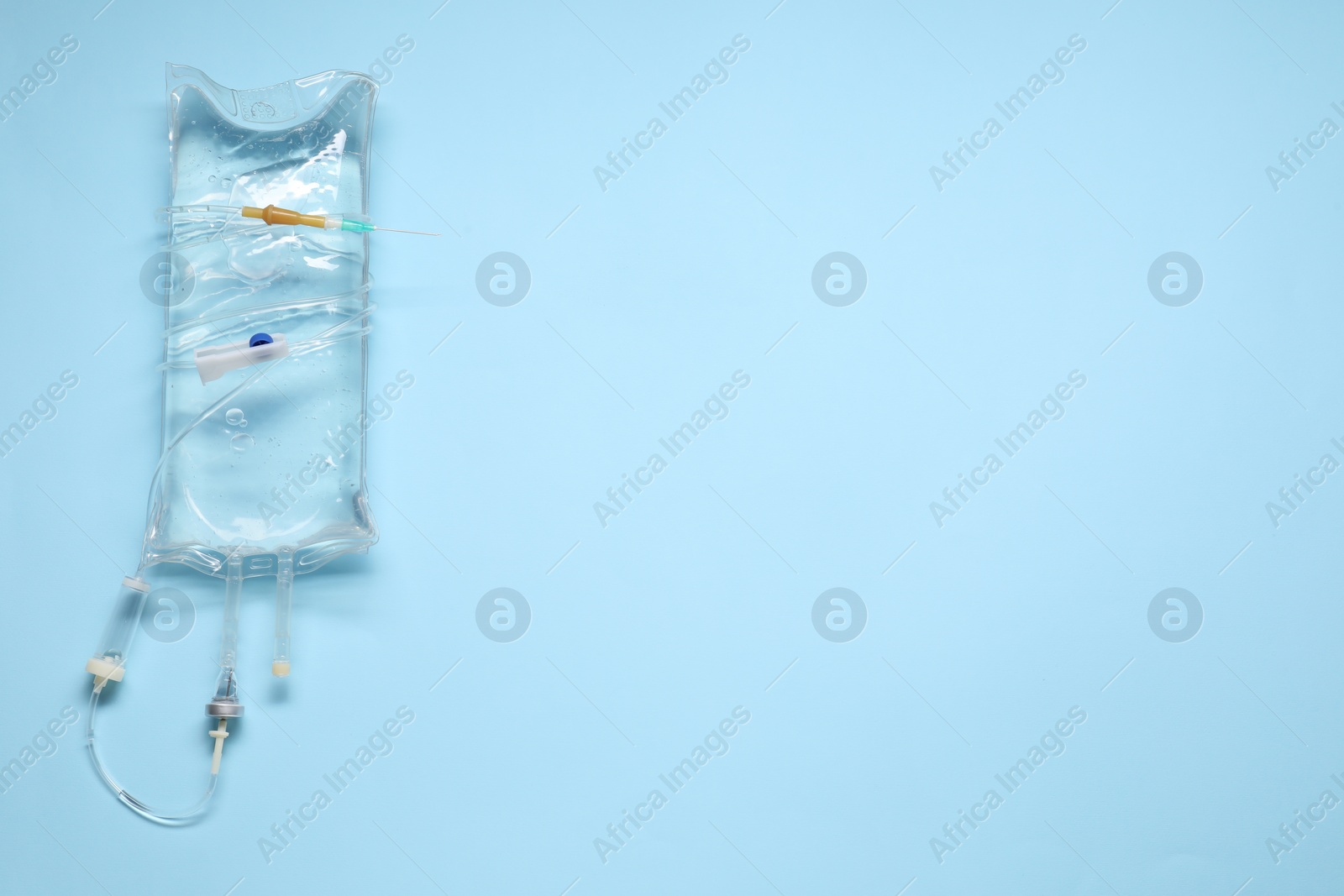 Photo of IV infusion set on light blue background, top view. Space for text