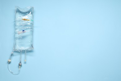 IV infusion set on light blue background, top view. Space for text