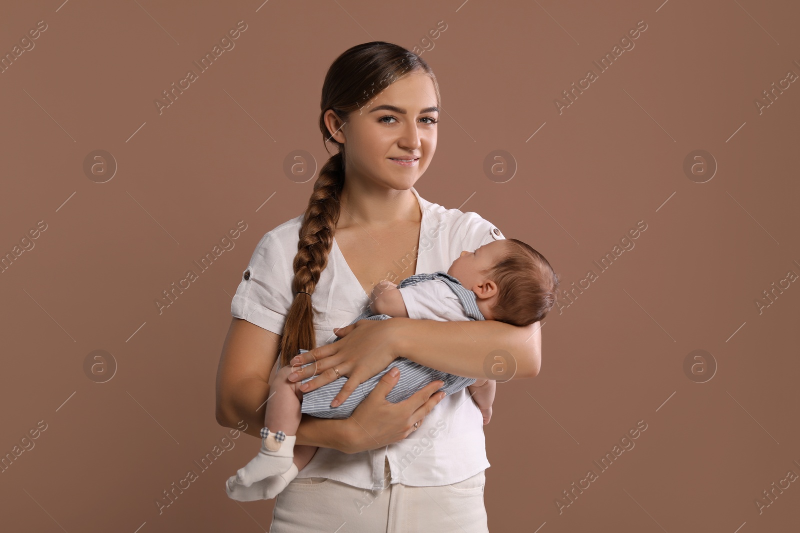 Photo of Mother holding her cute newborn baby on brown background