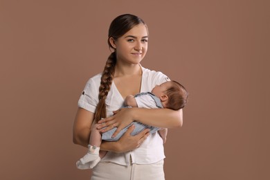 Mother holding her cute newborn baby on brown background