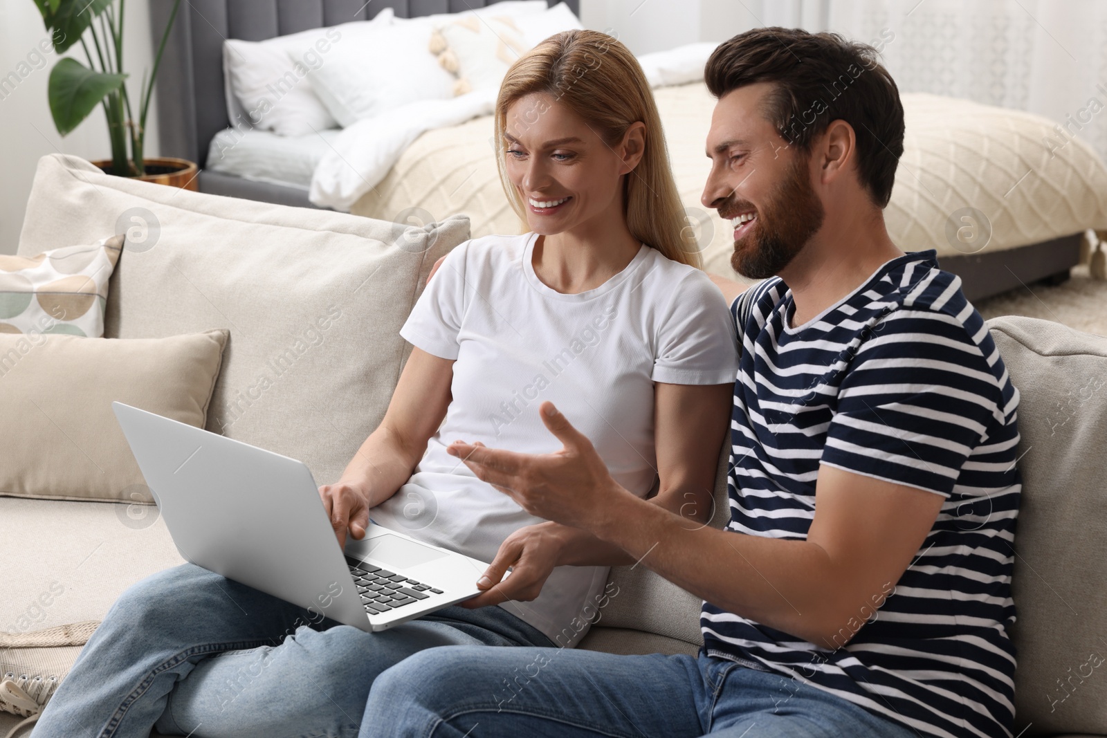 Photo of Happy couple with laptop on sofa at home