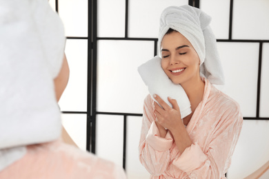 Young woman wiping face with towel near mirror in bathroom