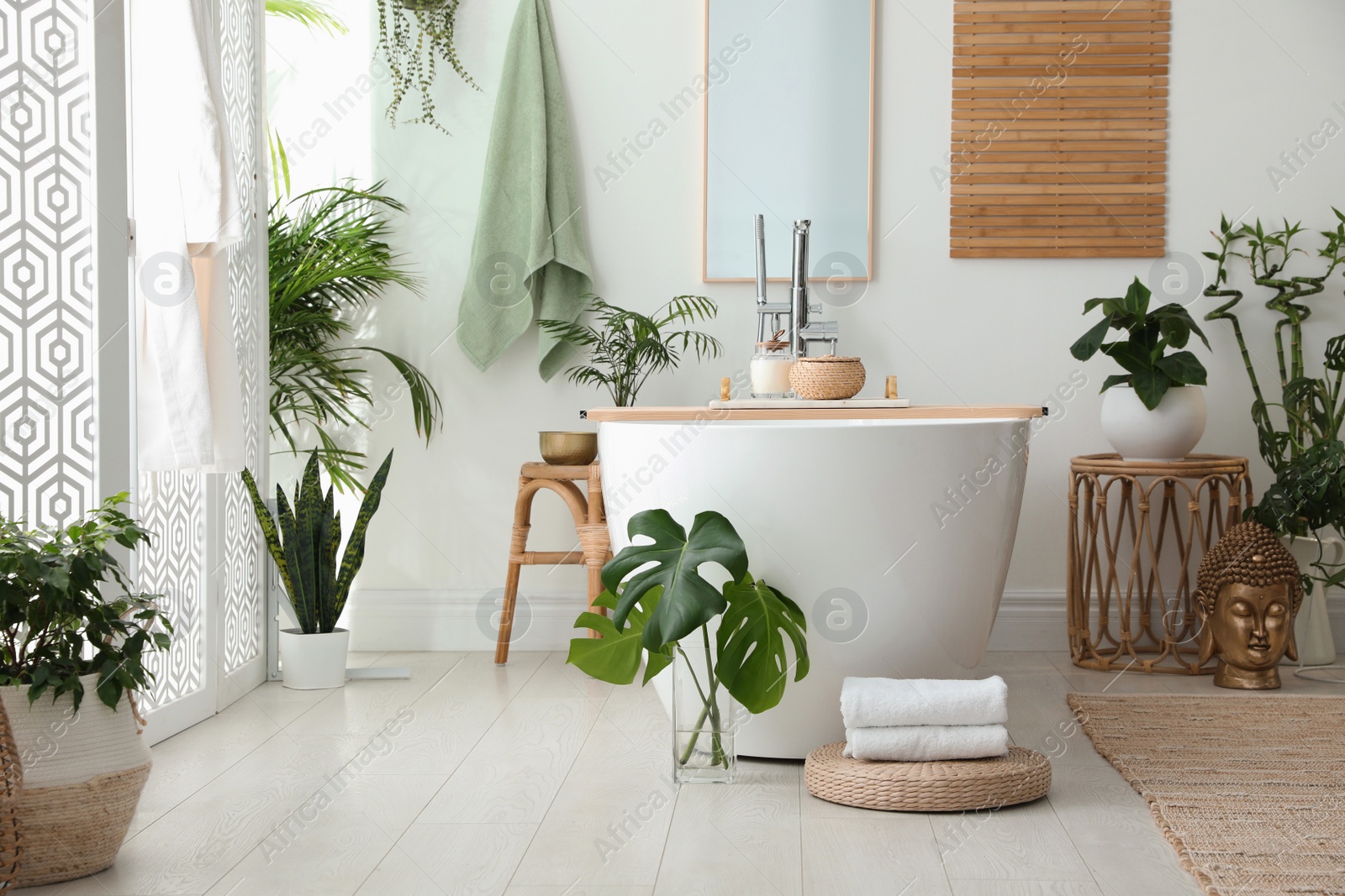 Photo of Stylish bathroom interior with modern tub, houseplants and beautiful decor. Home design